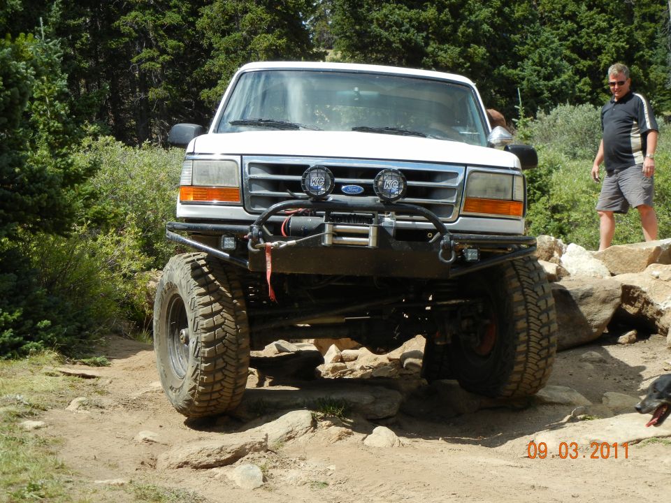 White 1996 Ford Bronco with winch and off-road tires on a rocky trail