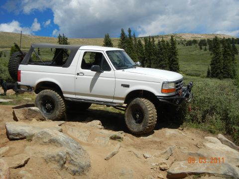 1996 Ford Bronco - 1996 Ford Bronco navigating a challenging rocky off-road course under a cloudy sky.