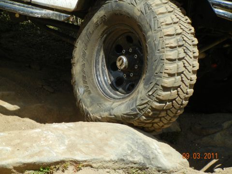 1996 Ford Bronco - A tire with aggressive tread is positioned on a rock, suggesting off-road use.