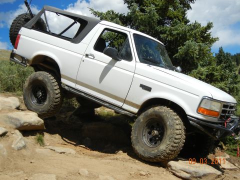 1996 Ford Bronco - White 1996 Ford Bronco navigating a rocky off-road trail.