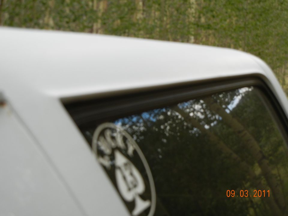 Close-up of white SUV roof and window with a circular sticker and date overlay