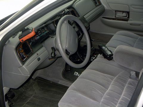 1999 Ford Crown Victoria - The interior of a 1998 Ford Crown Victoria is visible, equipped with a car phone and an orange device on the dashboard.