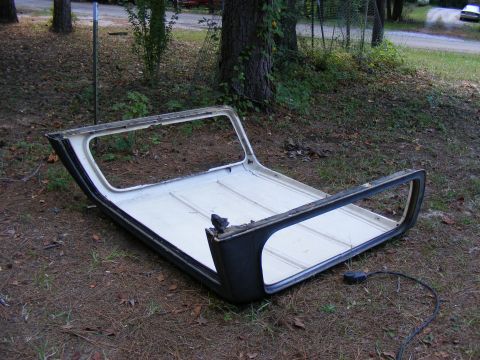 1978 Ford Bronco - This is a detached vehicle hardtop, possibly for a classic SUV, resting on the ground in a wooded area.