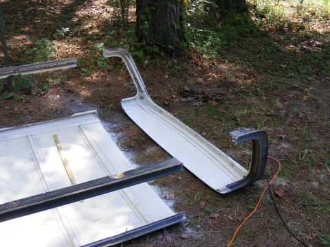 1978 Ford Bronco - Vehicle body panels and bumper components are laid out on the ground, suggesting a restoration or repair project.