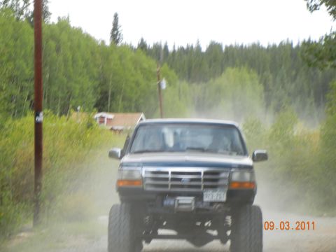 1996 Ford Bronco - A lifted 1996 Ford Bronco drives down a dusty road, kicking up a cloud of dirt.
