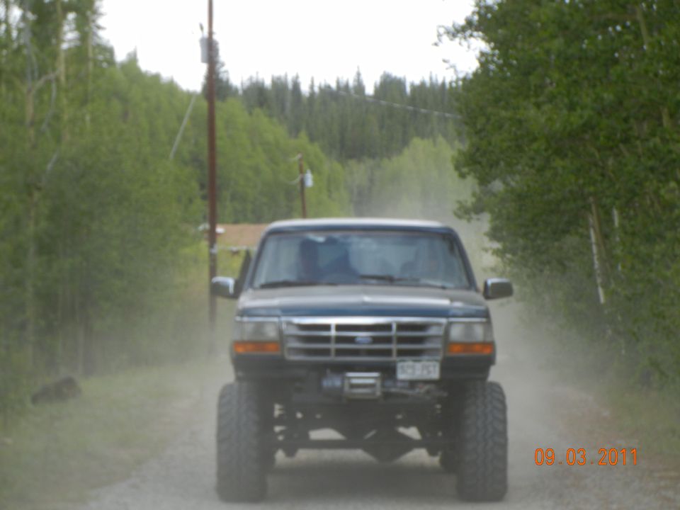 Lifted Ford pickup truck driving on a dirt road, kicking up dust