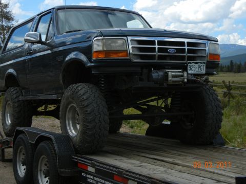 1996 Ford Bronco - A lifted 1996 Ford Bronco with a winch is loaded onto a trailer.