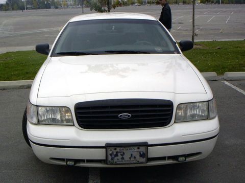 1999 Ford Crown Victoria - White Ford Crown Victoria parked in an empty lot with a person standing in the background.