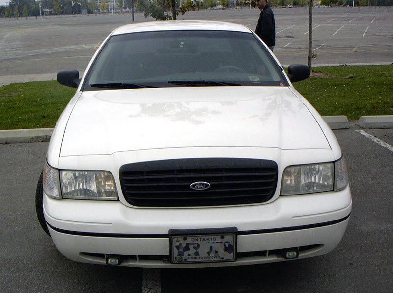 Front view of a white Ford Crown Victoria parked in a lot. Ontario license plate visible