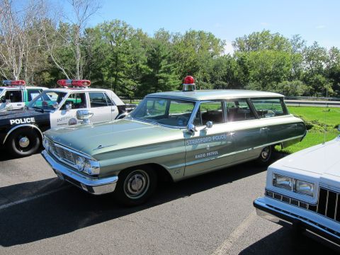 1991 Ford LTD Crown Victoria - restored light green Stratford Police Radio Patrol Ford station wagon with chrome trim sits among other classic cruisers.