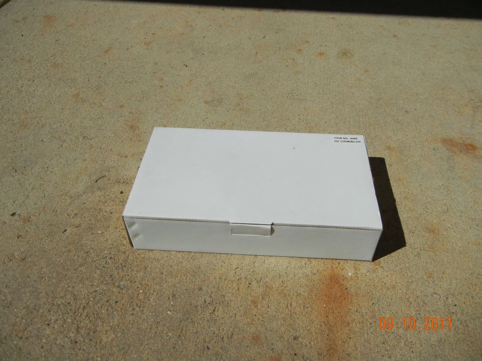 White cardboard box on concrete ground, with small text label on top right