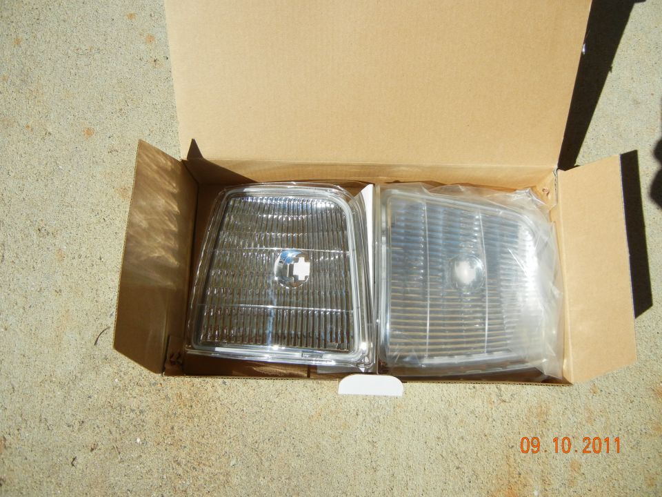 Two clear plastic car headlights in a cardboard box