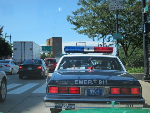 1991 Ford LTD Crown Victoria - Rear view of a blue Chevrolet Caprice police car lettered EMER 911 with a Connecticut MVC-1 plate stopped in city traffic.
