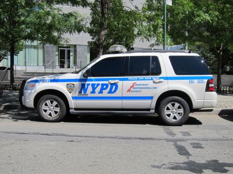 1991 Ford LTD Crown Victoria - white NYPD ESU police SUV with a blue stripe and POLICE DOG KEEP BACK lettering is parked curbside on a city street.