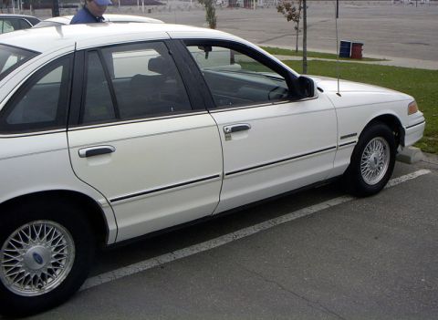 1999 Ford Crown Victoria - A white sedan is parked in a lot, viewed from the side.