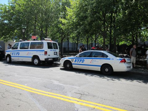 1991 Ford LTD Crown Victoria - white NYPD traffic enforcement van and a marked patrol sedan parked along a tree-lined street.