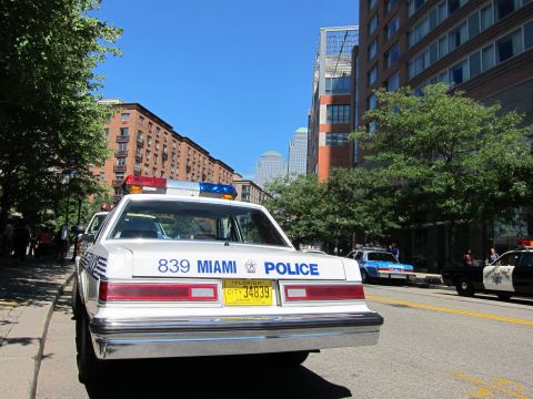1991 Ford LTD Crown Victoria - Rear view of a white vintage Miami Police sedan, number 839, with a Florida plate parked on a sunny urban street.