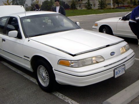 1999 Ford Crown Victoria - A white 1999 Ford Crown Victoria is shown with its hood open, parked next to another similar vehicle.
