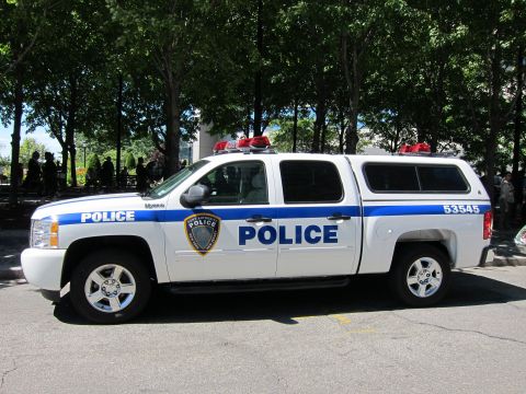 1991 Ford LTD Crown Victoria - Side view of a white-and-blue Chevrolet crew-cab police pickup, unit 53545, with light bar and bed cap.