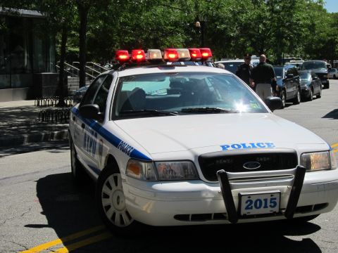 1991 Ford LTD Crown Victoria - white NYPD Ford Crown Victoria patrol car, unit 2015, with red emergency lights lit, parked on a sunny street.