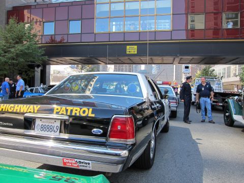 1991 Ford LTD Crown Victoria - Rear view of a black Ford Highway Patrol sedan with a California plate reading 888849, parked under an overpass near a flatbed truck.