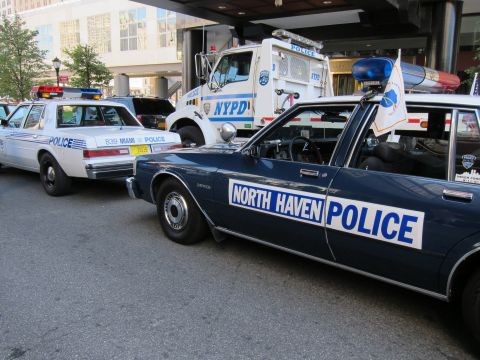 1991 Ford LTD Crown Victoria - dark blue Chevrolet sedan lettered North Haven Police sits beside a white Miami police car and an NYPD truck.