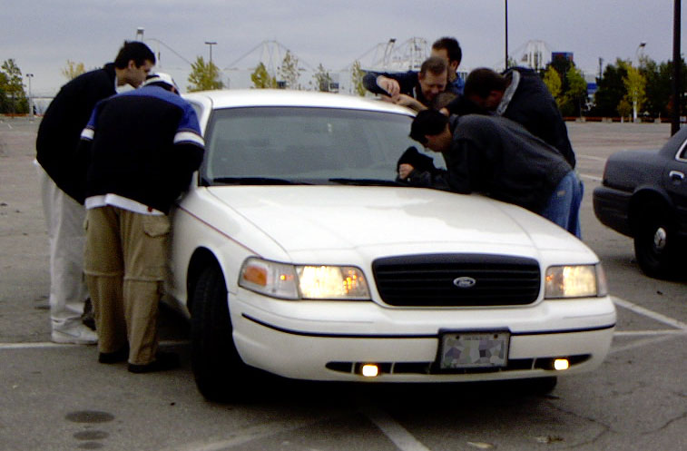 White 1999 Ford Crown Victoria front view with people gathered around the hood