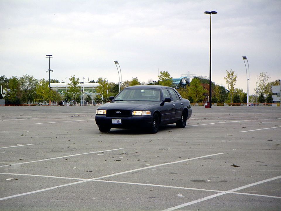 dark sedan parked in an empty lot, front view