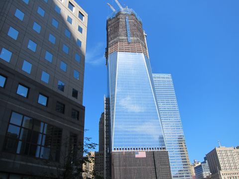 1991 Ford LTD Crown Victoria - tall glass skyscraper still under construction, with its upper crown unfinished, rises beside an older office building.