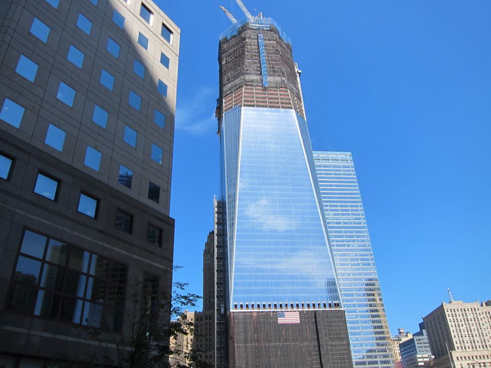 Glass skyscraper under construction with a crowned top against blue sky