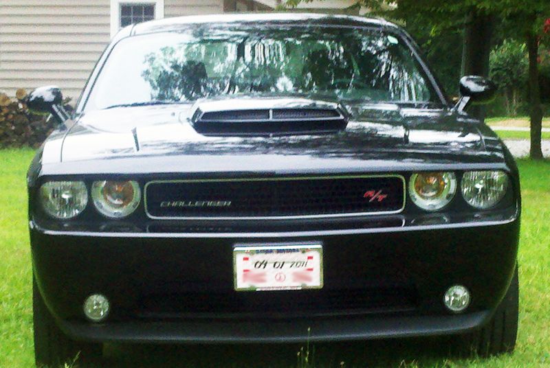 Front view of a black Dodge Challenger with a hood scoop and a license plate reading '01 DJ 701'