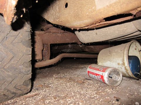 1991 Ford LTD Crown Victoria - The underside of a neglected vehicle, a worn tire and discarded cans on the ground.