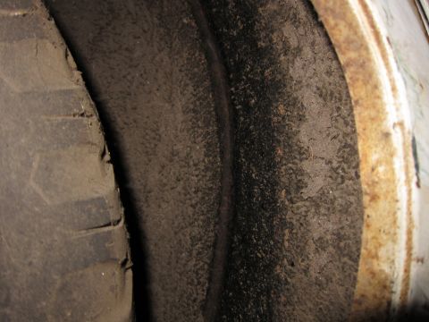 1991 Ford LTD Crown Victoria - A close-up view of a dirty wheel well and a worn tire, showing signs of age and use.