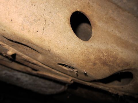 1991 Ford LTD Crown Victoria - Underside view of a rusty car frame, revealing structural details and openings.