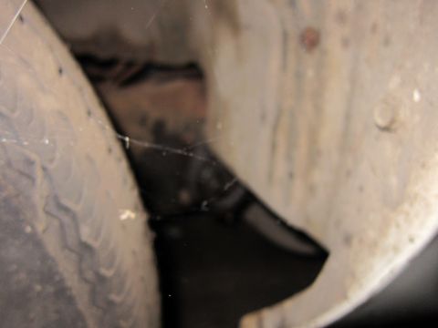 1991 Ford LTD Crown Victoria - A close-up view of a vehicle's tire and wheel well, showing dust and cobwebs.
