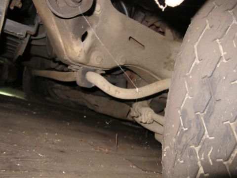1991 Ford LTD Crown Victoria - A close-up view of a vehicle's undercarriage reveals suspension parts and a tire, with a spiderweb present.