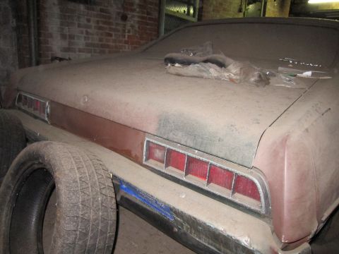 1991 Ford LTD Crown Victoria - Rear view of a dusty car with horizontal taillights and a spare tire nearby.