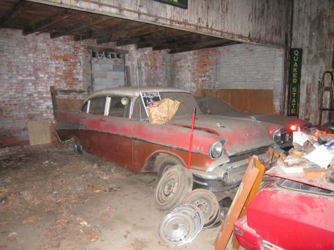 1991 Ford LTD Crown Victoria - A vintage Chevrolet sits in a cluttered garage, covered in dust, with spare tires and parts nearby.