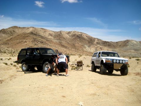 1996 Ford Bronco - Two 1996 Ford Broncos are parked in a desert landscape with mountains visible under a blue sky.