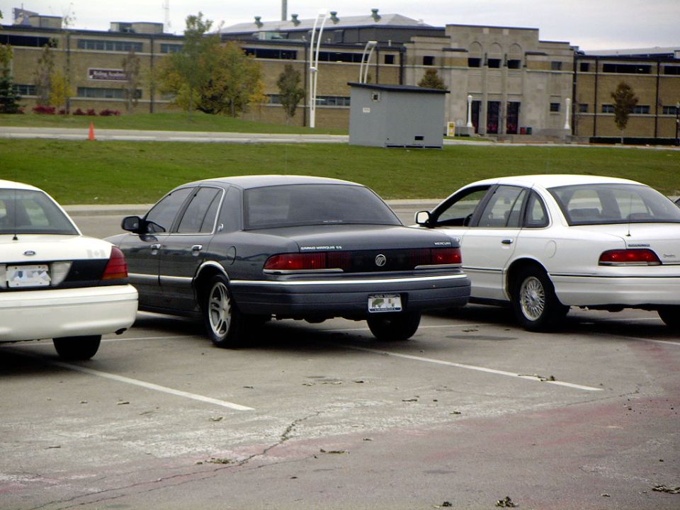 Dark green Mercury Grand Marquis sedan parked between two Ford sedans