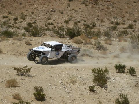 1996 Ford Bronco - A custom-built off-road race truck navigates a dusty desert terrain during a competition.