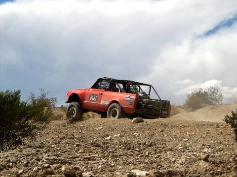 1996 Ford Bronco - A modified off-road truck navigates a challenging dirt course, kicking up dust.