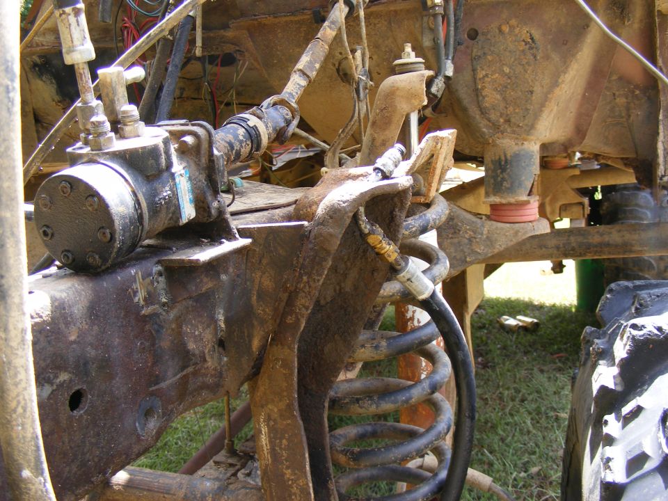 close-up of rusty off-road vehicle suspension with hydraulic lines and coil spring