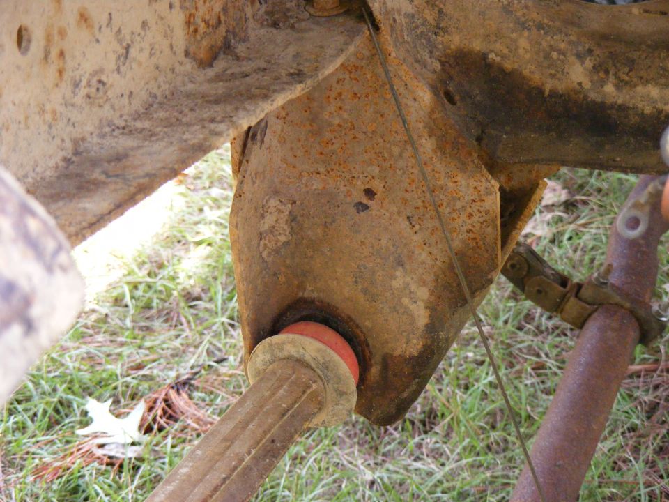 Rusty suspension part with red bushing and metal clamp