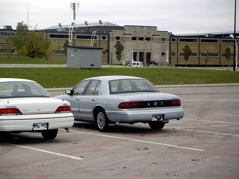 Silver sedan parked in a lot, rear view. Mud flaps say "FORD"