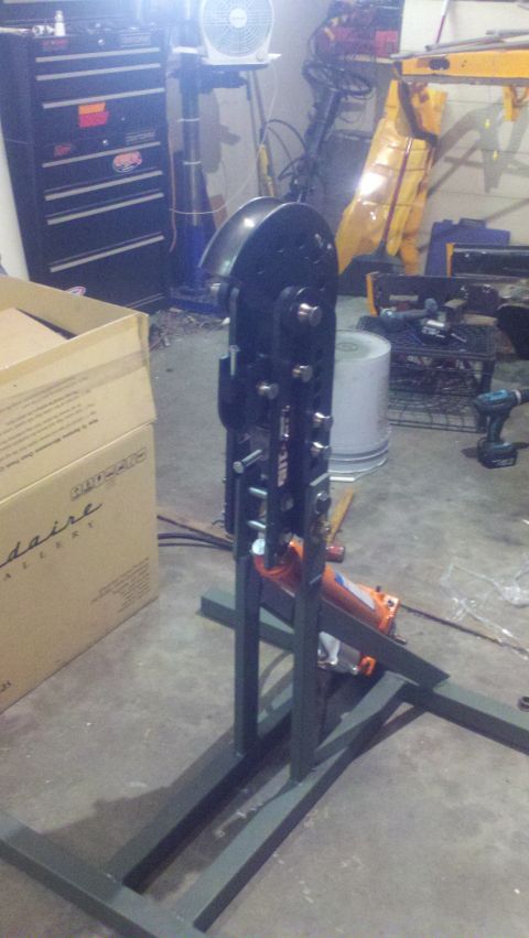 1988 Ford Bronco - A metal fabrication tool with an orange hydraulic jack is set up on a stand in a cluttered garage.