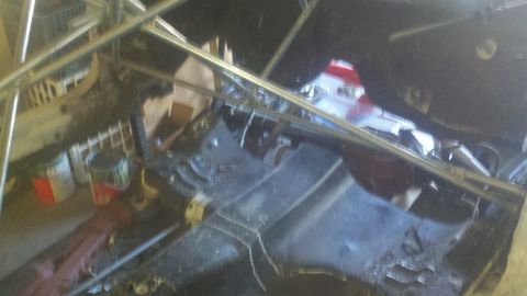 1978 Ford Mustang II - The underside of a vehicle is visible, obscured by scaffolding and workshop clutter.