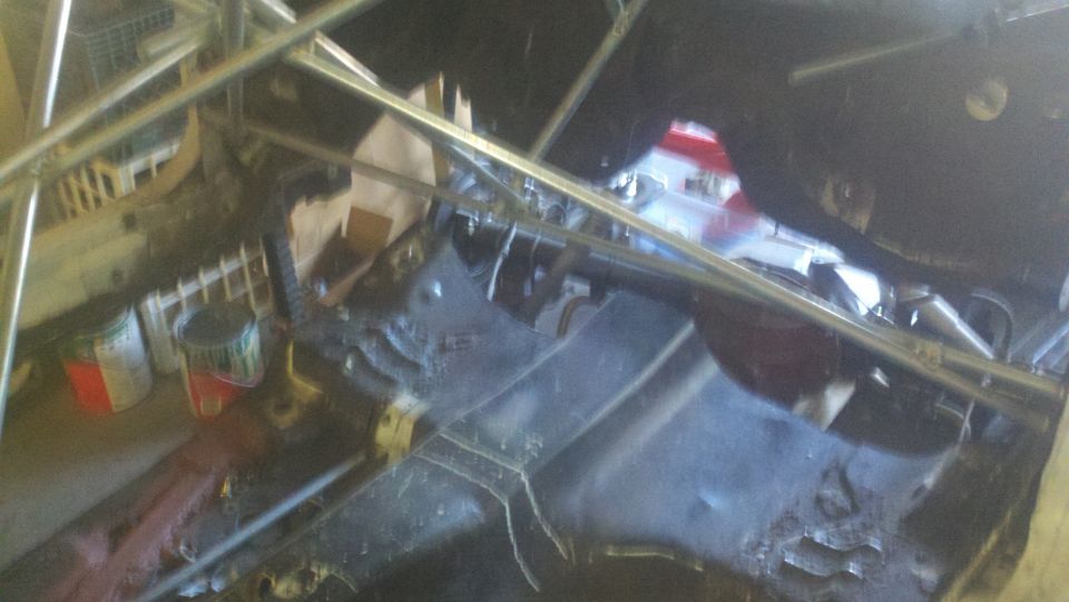 Undercarriage of a car with scaffolding, paint cans, and debris