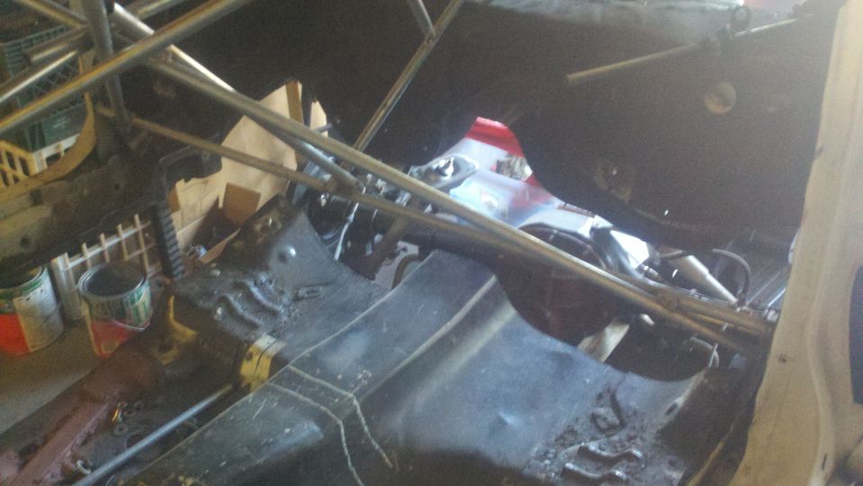 Interior of a car with a roll cage installed. Floor is bare metal and appears worn