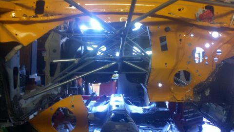 1978 Ford Mustang II - The interior of a car is heavily modified with a roll cage and exposed yellow metal.
